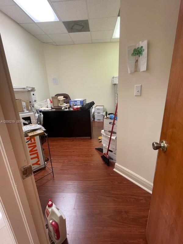 A small office features wood-look flooring, a dark desk, and stacked storage boxes — 12900 SW 128th St # 104, Miami FL 33186, MIAMI, FL