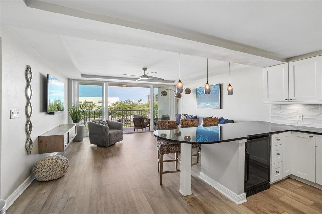 An open-concept living area features a kitchen island, dining seating, and a balcony view — 223 ISLAND WAY UNIT 4C, CLEARWATER BEACH, FL