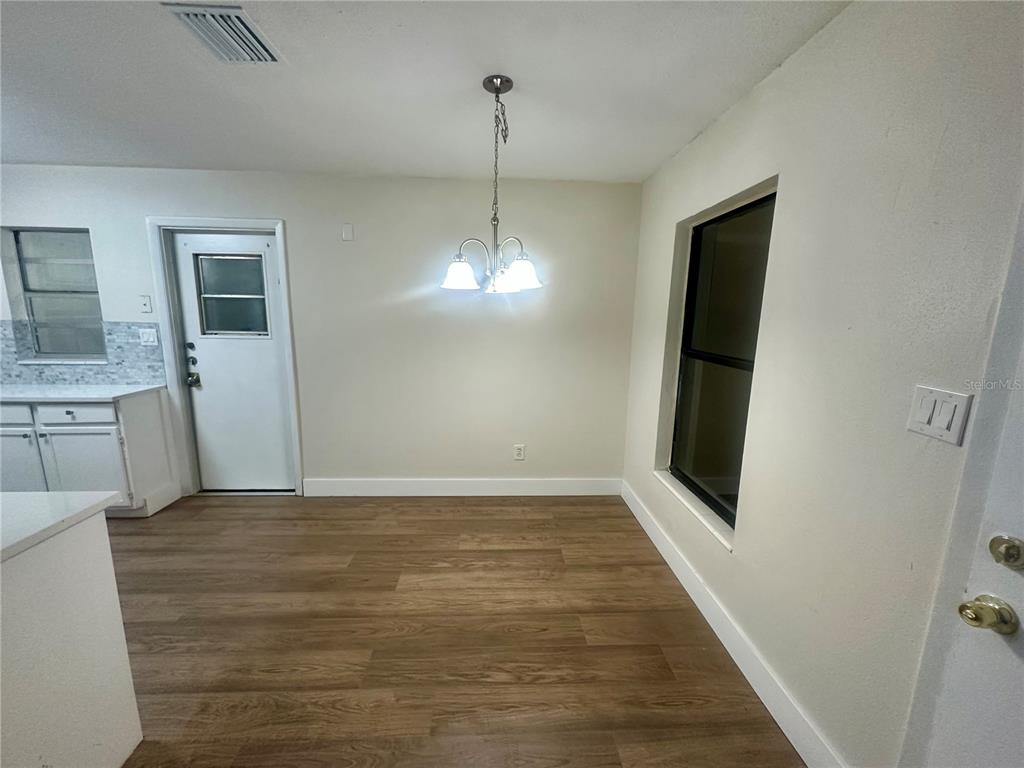 A dining area features wood-look flooring, a white door, a window, and a hanging light fixture — 2146 AARON AVENUE, ORLANDO, FL