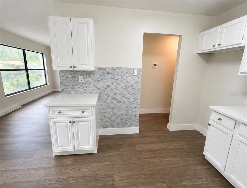 A kitchen features white cabinets, a mosaic tile backsplash, and wood-look flooring — 2146 AARON AVENUE, ORLANDO, FL