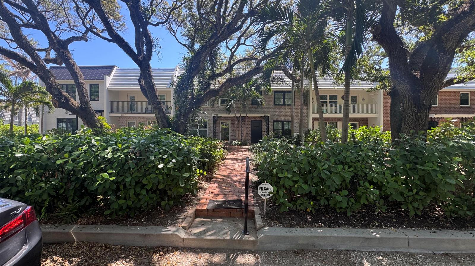A brick walkway leads to the entrance of a two-story townhouse with lush landscaping — 2704 Cardinal Drive, Vero Beach FL 32963, VERO BEACH, FL