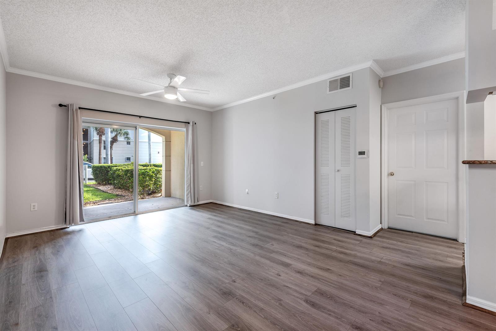 An empty living room features wood-look flooring, a ceiling fan, and sliding glass doors to a patio — 1106 Tuscany Way, Boynton Beach FL 33435, BOYNTON BEACH, FL