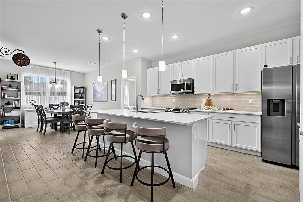 A modern kitchen features white cabinets, a large island with bar seating, and tile flooring — 30 POPLAR DRIVE, PALM COAST, FL