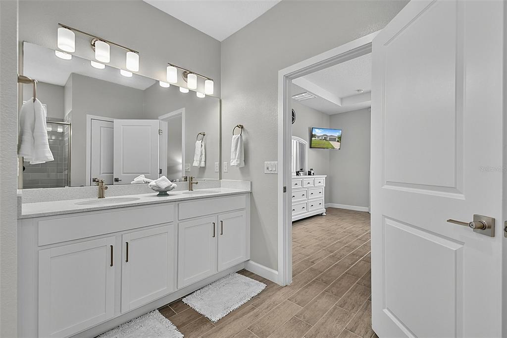A bathroom with a double vanity, white cabinets, and a doorway leading to a bedroom — 30 POPLAR DRIVE, PALM COAST, FL