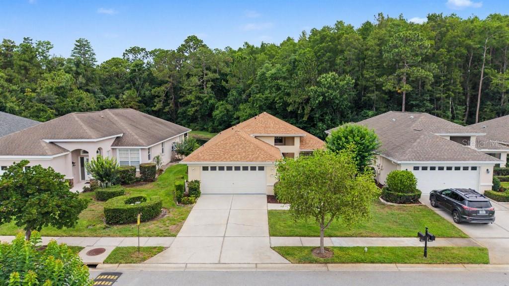 A suburban street view of three single-story houses with driveways and surrounding trees — 1812 ORCHARDGROVE AVENUE, NEW PORT RICHEY, FL