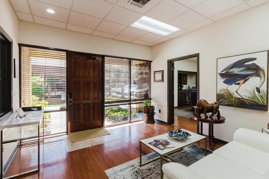 A waiting room features wood floors, a white sofa, a coffee table, and a wooden door — 611 DRUID ROAD E UNIT 707 & 708, CLEARWATER, FL