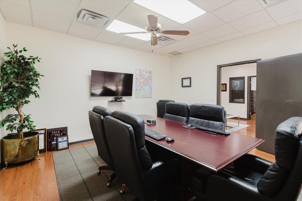A conference room features a long wooden table, black leather chairs, and a wall-mounted television — 611 DRUID ROAD E UNIT 707 & 708, CLEARWATER, FL