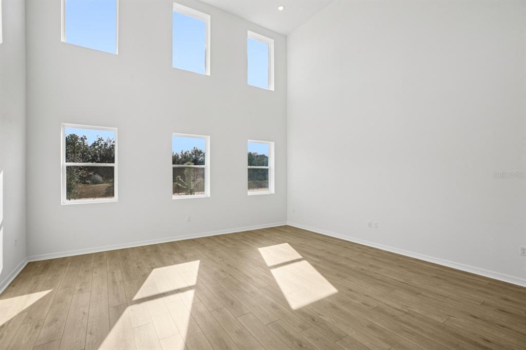 An empty room with high ceilings, light wood-look flooring, and two rows of windows — 17625 LAKE STAR ROAD, WINTER GARDEN, FL