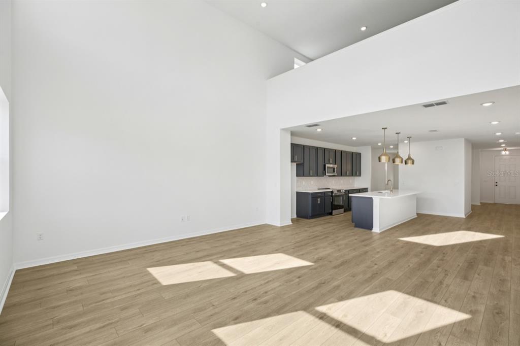 An open-concept living area with high ceilings, light wood flooring, and a modern kitchen — 17625 LAKE STAR ROAD, WINTER GARDEN, FL