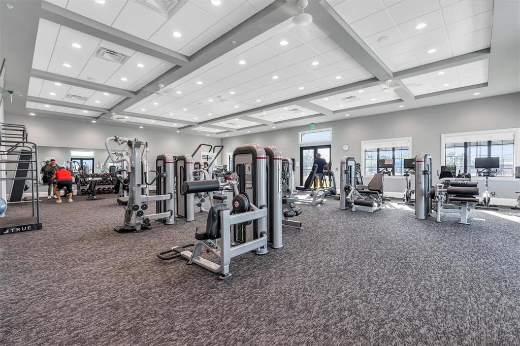 A spacious gym features various weight machines, cardio equipment, recessed lighting, and gray carpeting — 14121 HERITAGE LANDING BOULEVARD UNIT 725, PUNTA GORDA, FL