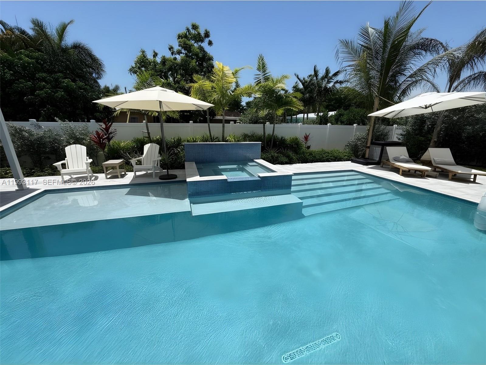 A swimming pool with an integrated spa and lounge chairs sits in a backyard — 426 SE 3rd St, Dania Beach FL 33004, DANIA BEACH, FL