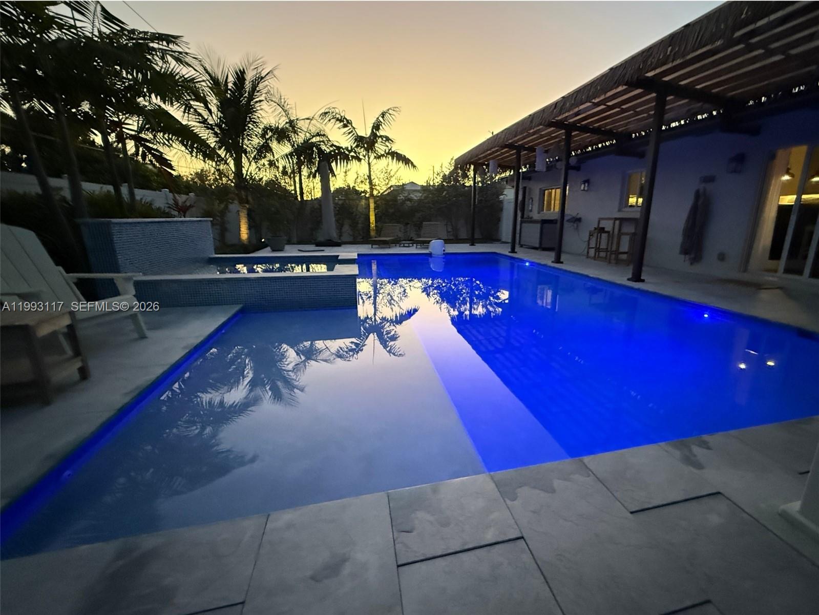 A backyard swimming pool with a spa and a covered patio at sunset — 426 SE 3rd St, Dania Beach FL 33004, DANIA BEACH, FL