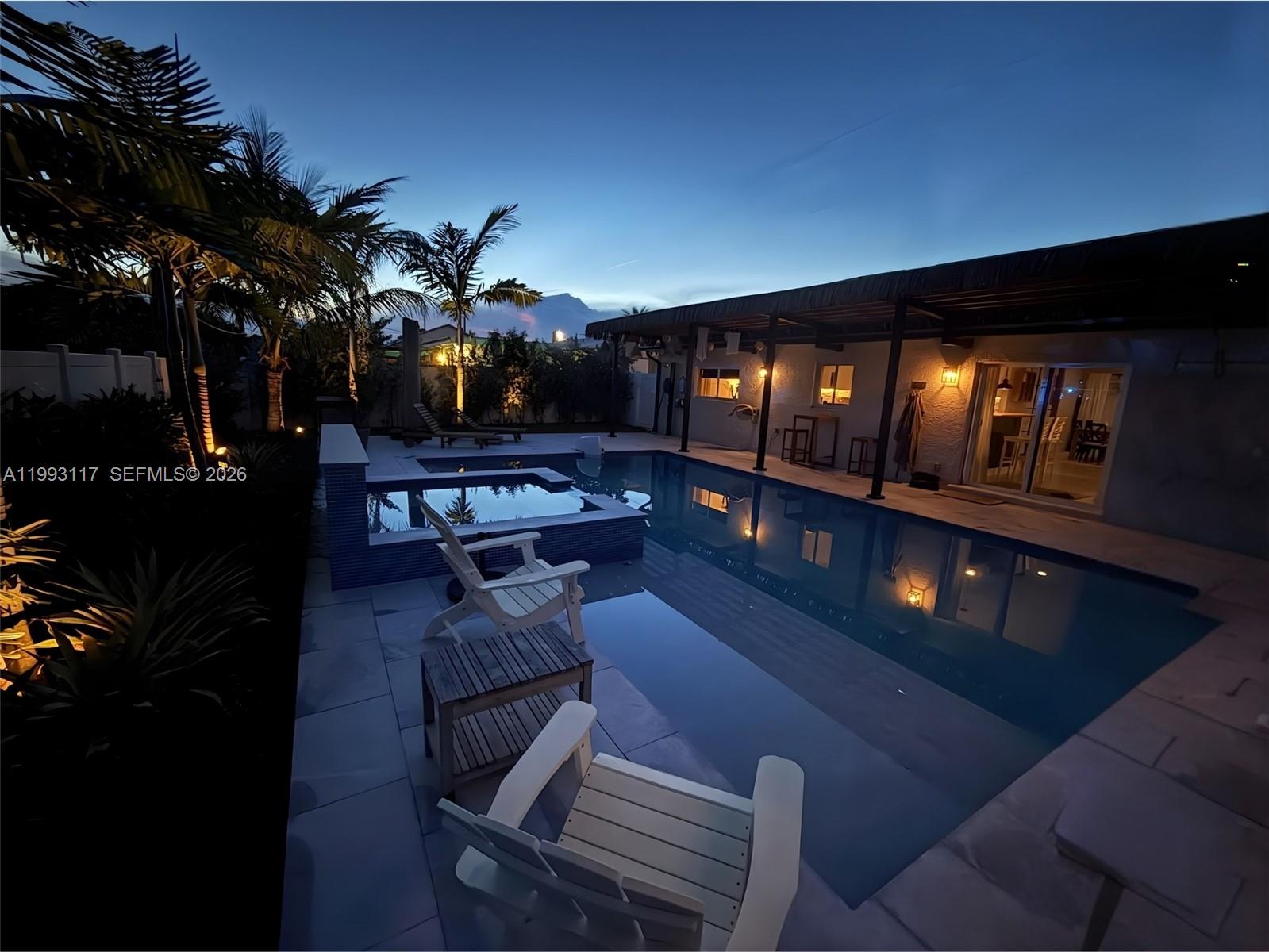 An outdoor patio features a swimming pool, a hot tub, and lounge chairs at dusk — 426 SE 3rd St, Dania Beach FL 33004, DANIA BEACH, FL