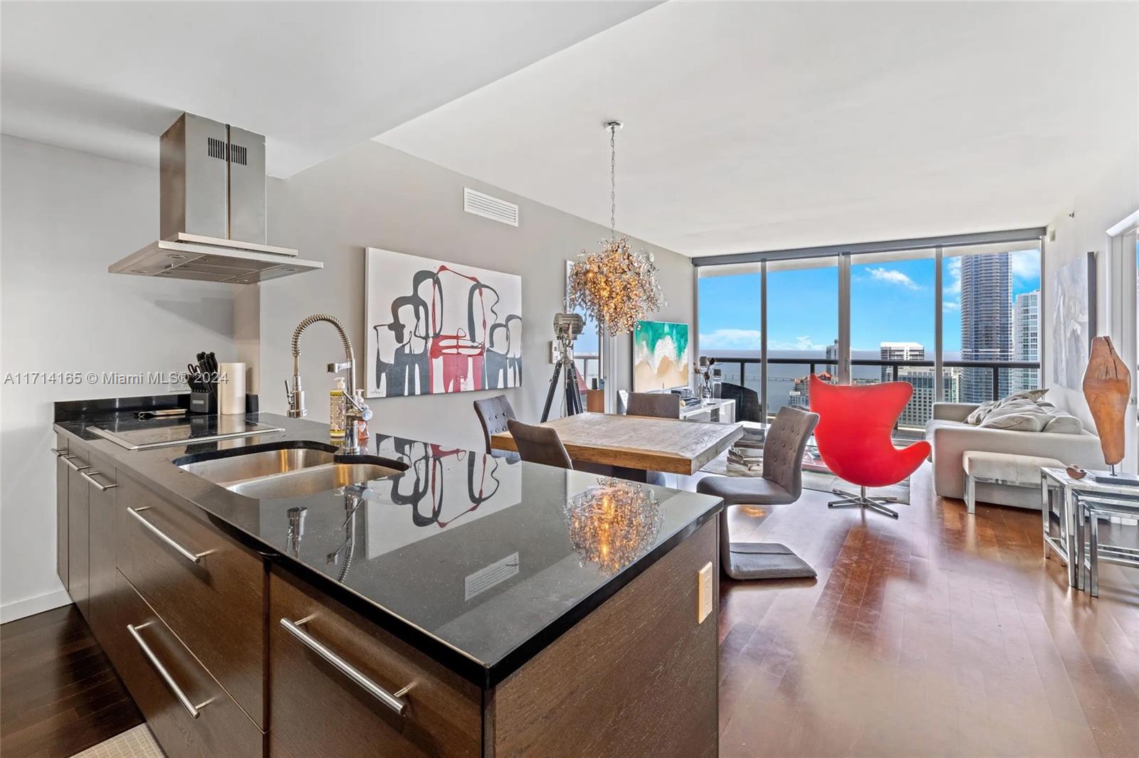 A modern kitchen with dark wood cabinets and black countertops opens into a living area — 495 Brickell Ave # 4805, Miami FL 33131, MIAMI, FL