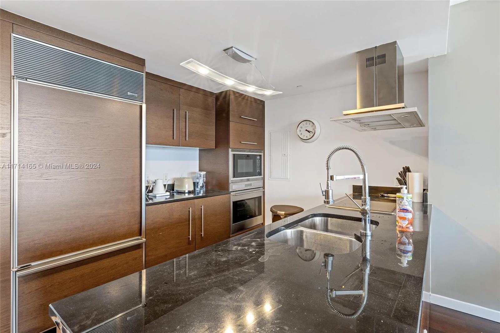 A modern kitchen features dark wood cabinetry, a black granite island, and stainless steel appliances — 495 Brickell Ave # 4805, Miami FL 33131, MIAMI, FL