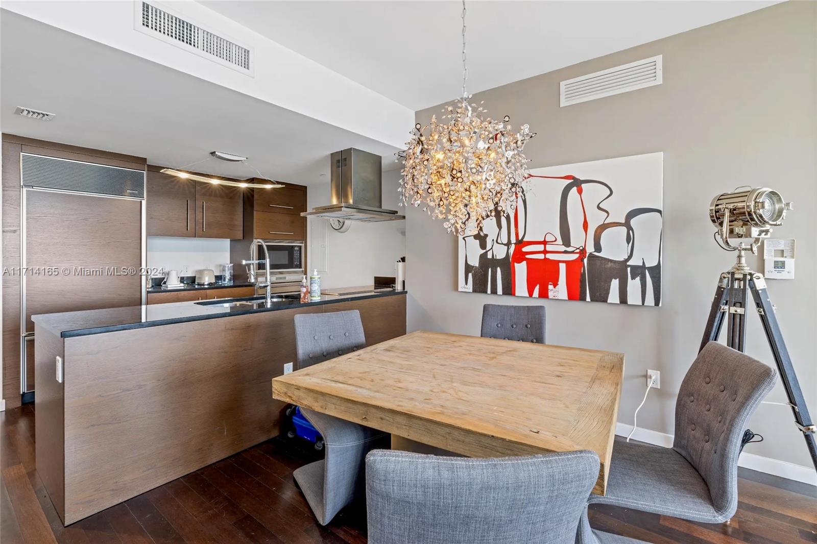 A dining area with a wooden table, gray chairs, and a modern chandelier — 495 Brickell Ave # 4805, Miami FL 33131, MIAMI, FL