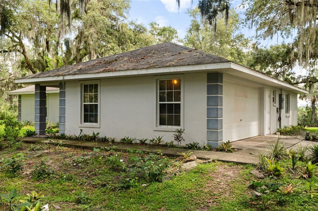 A single-story house with a white stucco exterior, gray corner accents, and a shingled roof — 7938 JACKSONS RIVER ROAD, LEESBURG, FL
