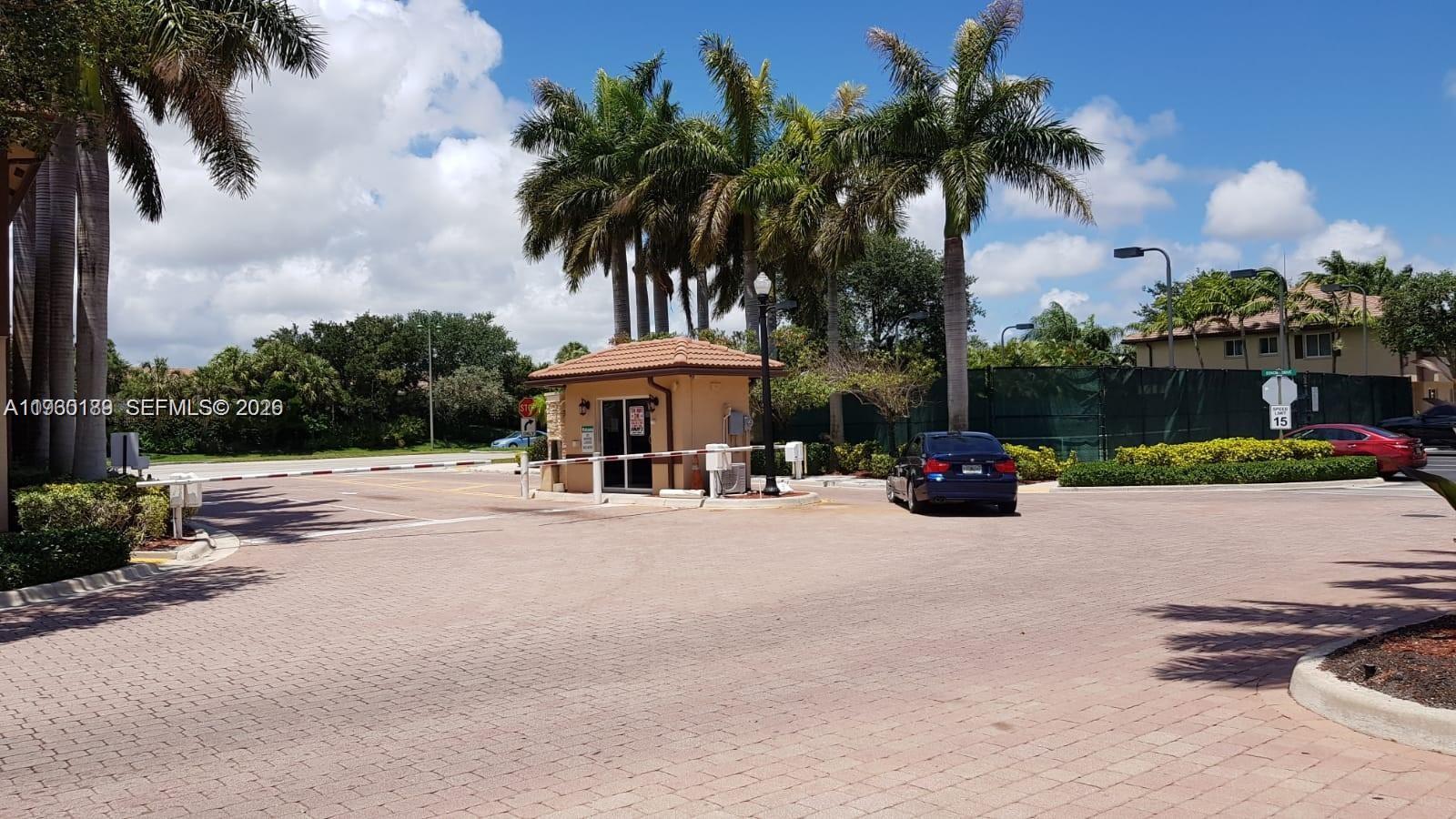 A gated community entrance features a guardhouse, palm trees, and a paved driveway — 3525 Sonoma Dr, Riviera Beach FL 33404, RIVIERA BEACH, FL