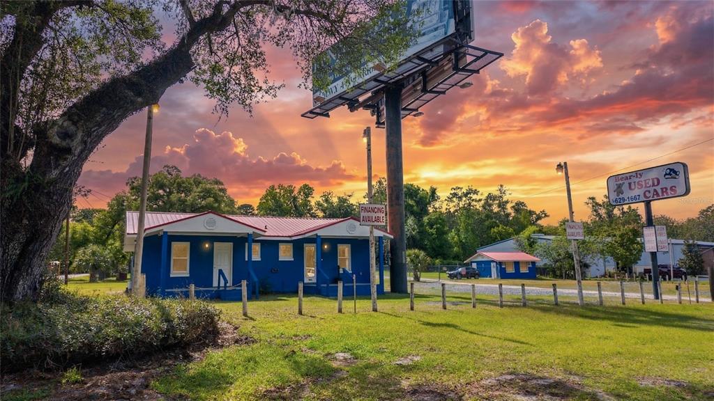 A blue building with a red roof stands under a sunset sky near a billboard — 6710 S PINE AVENUE, OCALA, FL