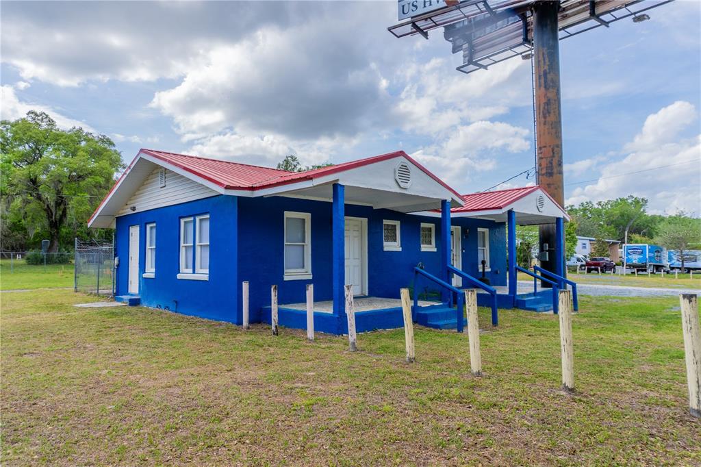 A blue, single-story building with a red metal roof sits on a grassy lot — 6710 S PINE AVENUE, OCALA, FL