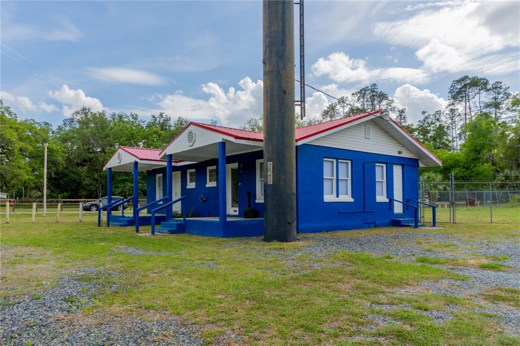 A bright blue, single-story building with a red metal roof sits on a gravel lot — 6710 S PINE AVENUE, OCALA, FL