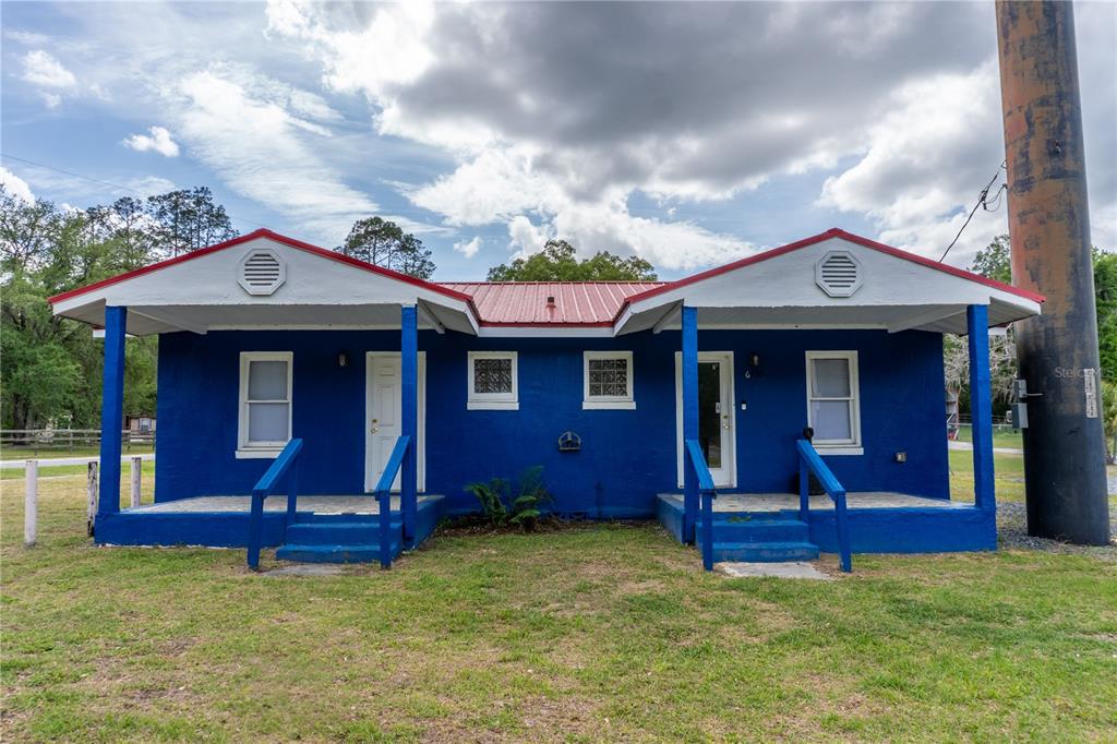 A blue, single-story duplex with two front porches and a red metal roof — 6710 S PINE AVENUE, OCALA, FL
