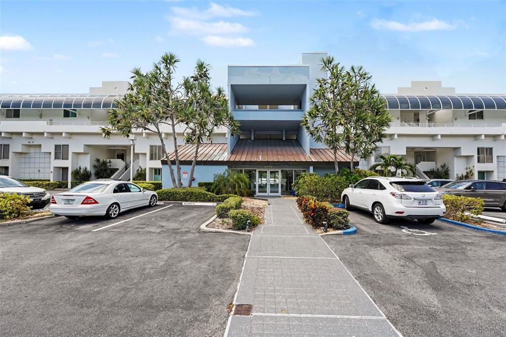 A multi-story building exterior features a central blue entrance with a walkway and parking — 5279 ISLA KEY BLVD S UNIT 410, ST PETERSBURG, FL