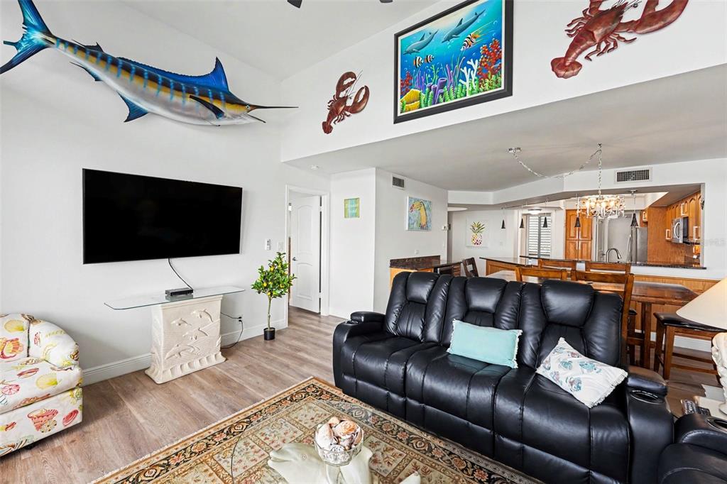 A living room features a black leather sofa, a wall-mounted television, and nautical wall decor — 5279 ISLA KEY BLVD S UNIT 410, ST PETERSBURG, FL