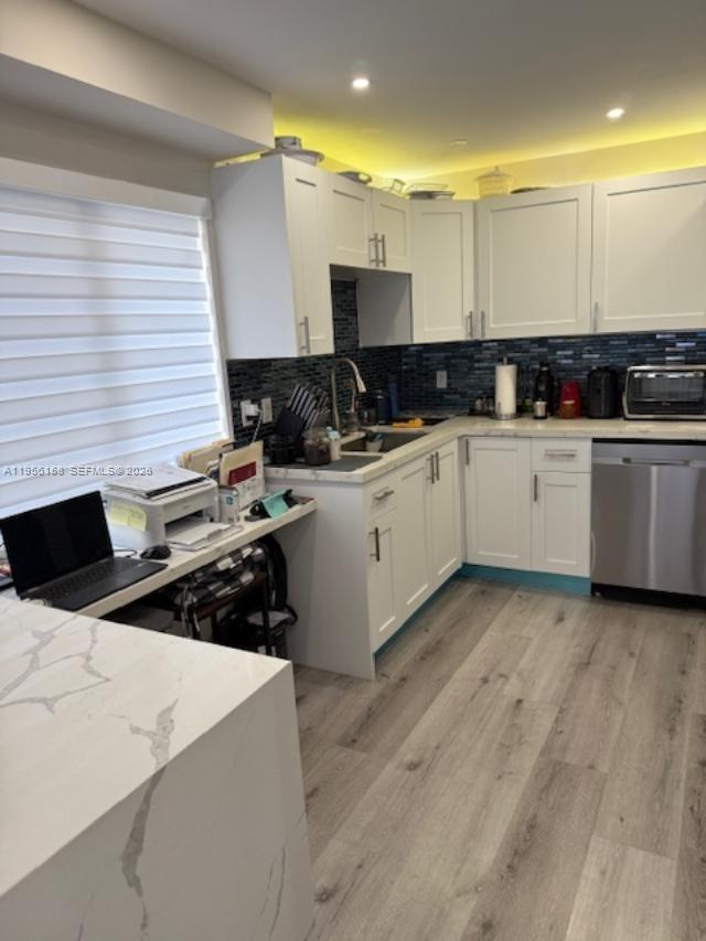 A kitchen features white cabinets, a blue tiled backsplash, and a light-colored countertop — 1700 Pierce St # 204, Hollywood FL 33020, HOLLYWOOD, FL