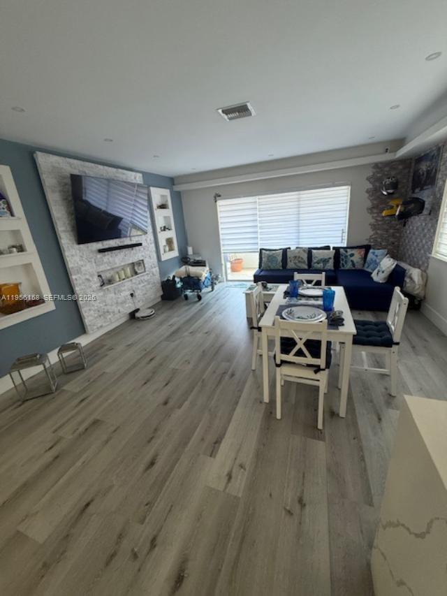 A living and dining area features light wood-look flooring, a stone-accented wall, and blue furniture — 1700 Pierce St # 204, Hollywood FL 33020, HOLLYWOOD, FL