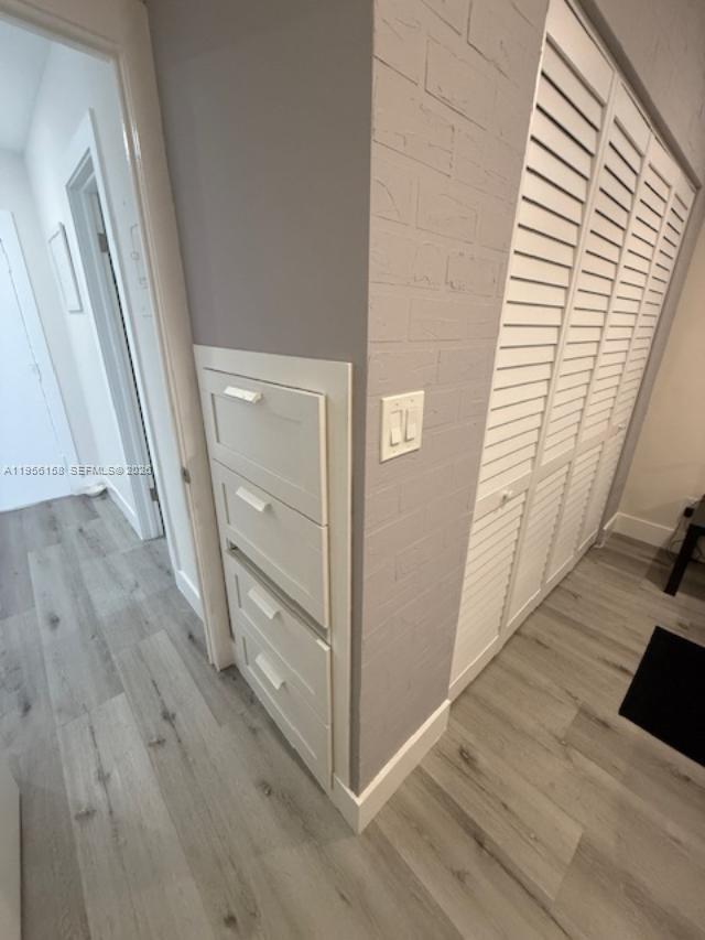 A hallway features light wood flooring, a built-in three-drawer unit, and white louvered closet doors — 1700 Pierce St # 204, Hollywood FL 33020, HOLLYWOOD, FL