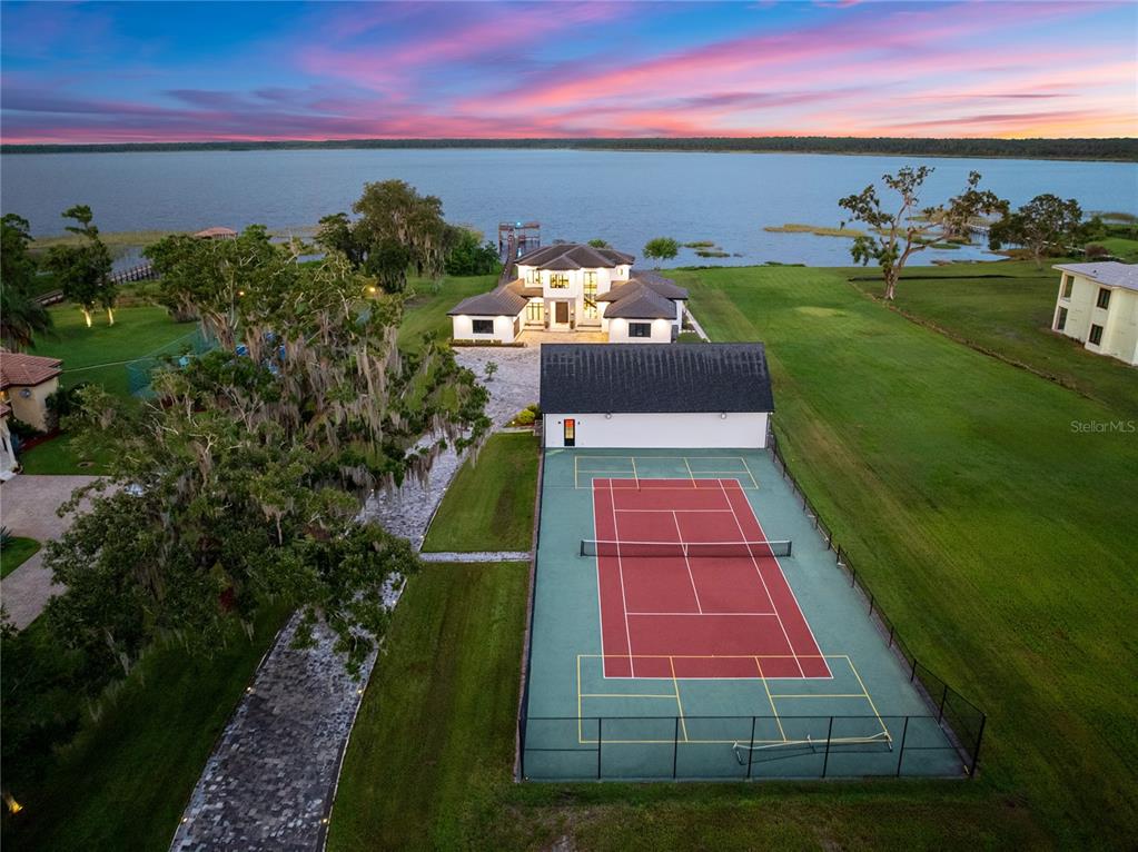 An aerial view shows a house with a tennis court and a lake in the background — 13395 KIRBY SMITH ROAD, ORLANDO, FL