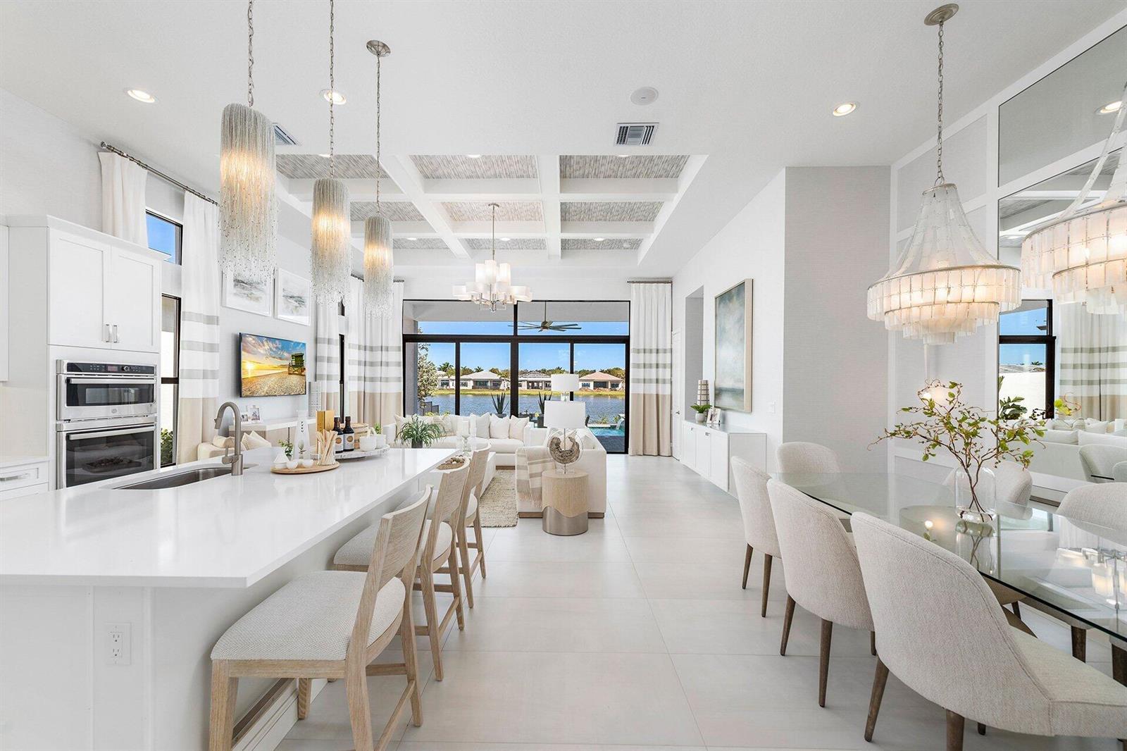 A bright, open-concept kitchen, dining, and living area features white cabinetry, tile floors, and lake views — 9374 Mountain Pne Grove, Boynton Beach FL 33473, BOYNTON BEACH, FL