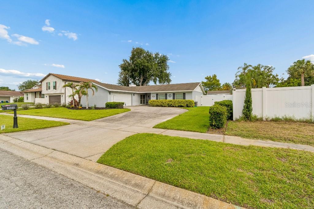 A single-story house with a concrete driveway, a white fence, and a manicured lawn — 4009 MOUNTAIN SPRINGS LANE, TAMPA, FL