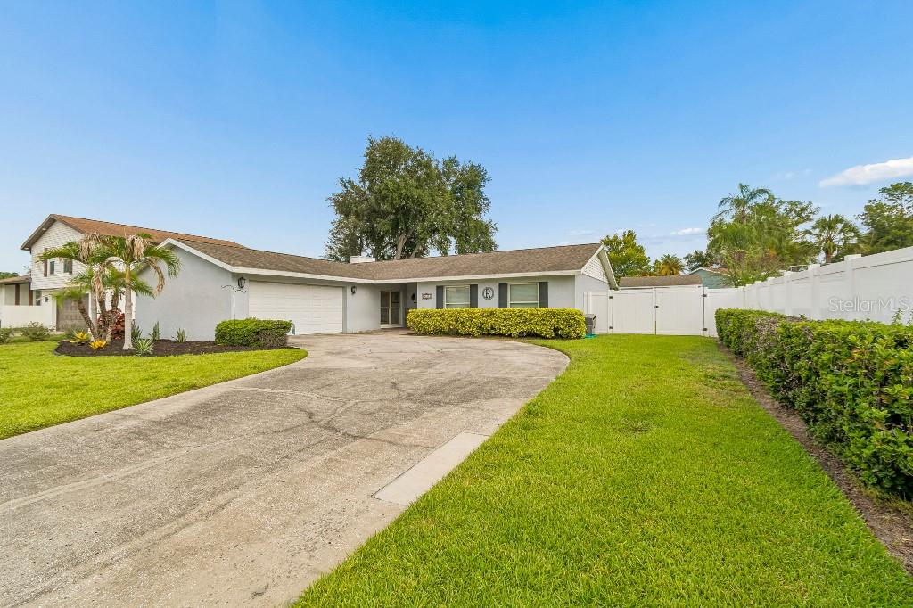 A single-story house with a white garage, concrete driveway, and a white privacy fence — 4009 MOUNTAIN SPRINGS LANE, TAMPA, FL