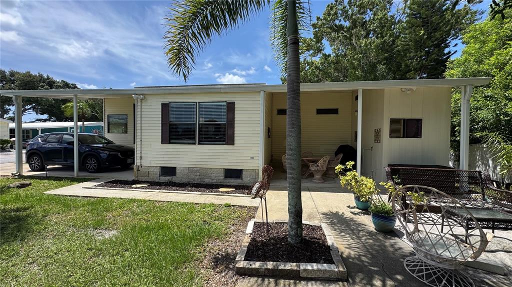 A single-story house with light yellow siding, a carport, and a palm tree in front — 1001 STARKEY ROAD UNIT 350, LARGO, FL