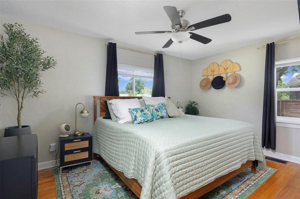 A bedroom features a bed with a light green quilt, a ceiling fan, and hardwood floors — 4332 9TH AVENUE N, ST PETERSBURG, FL