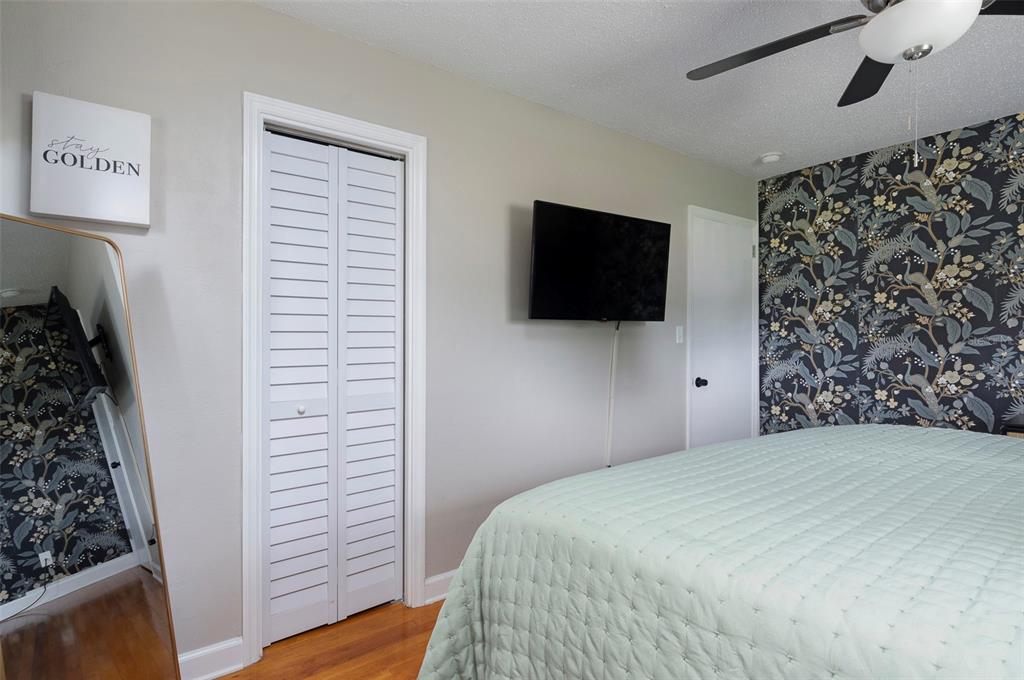 A bedroom features a bed with a light green quilt, floral wallpaper, and a wall-mounted television — 4332 9TH AVENUE N, ST PETERSBURG, FL