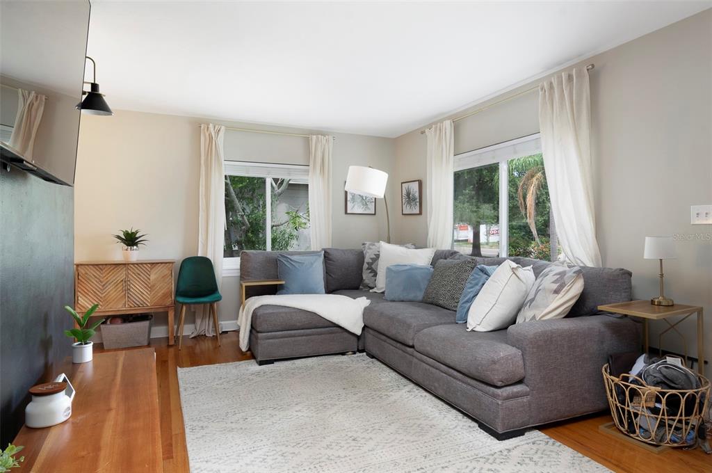 A living room features a gray sectional sofa, hardwood floors, and two windows with curtains — 4332 9TH AVENUE N, ST PETERSBURG, FL