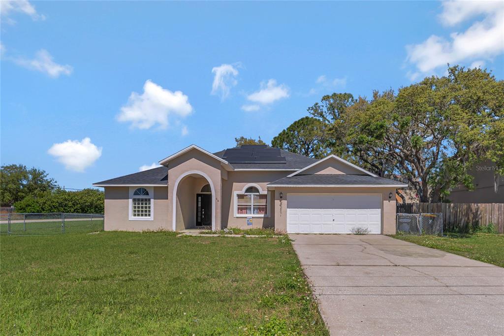 A single-story house with a beige stucco exterior, a two-car garage, and a solar roof — 68 HERRING COURT, KISSIMMEE, FL