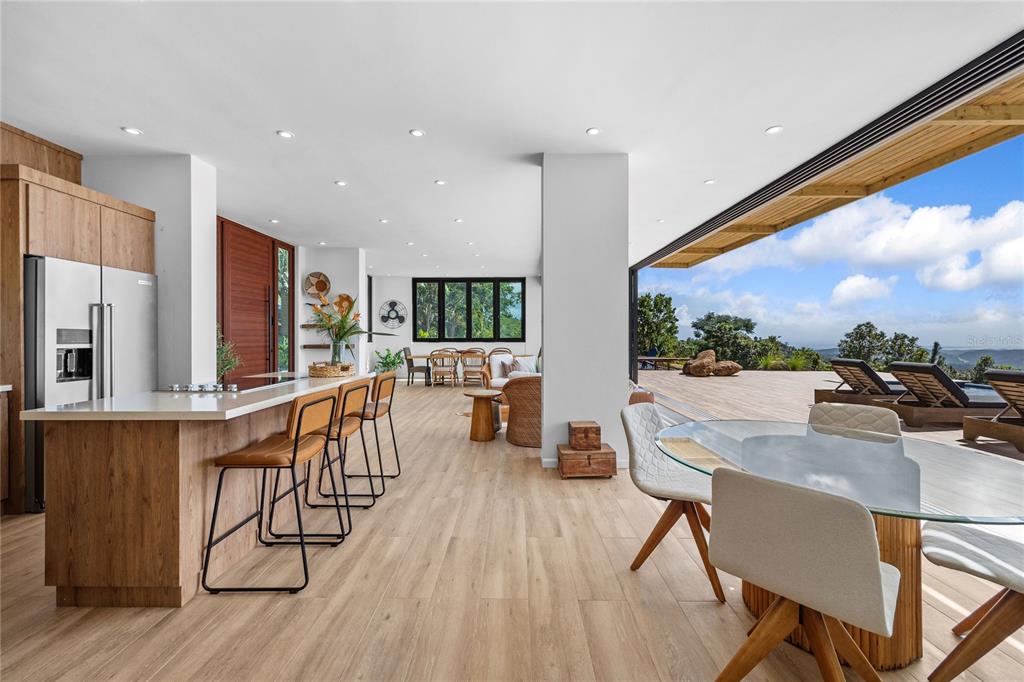 An open-concept kitchen and dining area features wood cabinetry, a breakfast bar, and outdoor views — 24-2 Bo. Pena Pobre KM 2.3 VISTA DEL ESTE, NAGUABO, PR