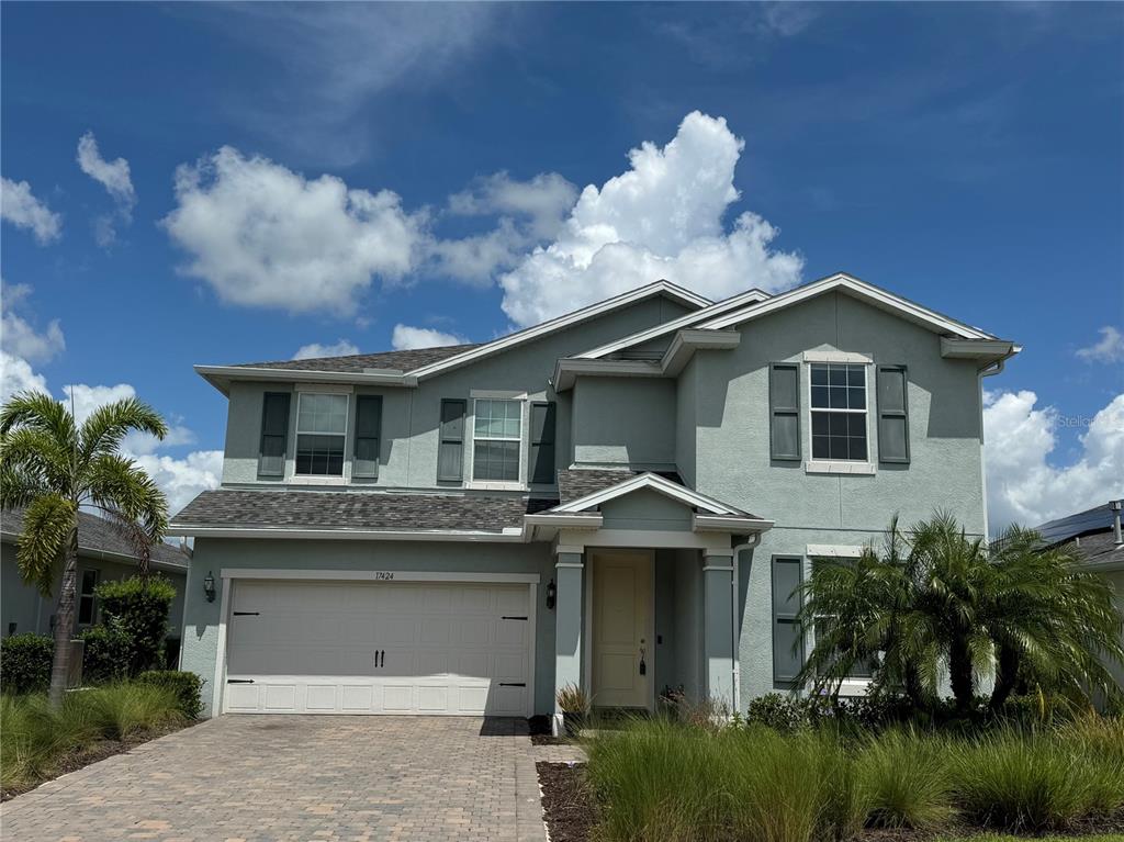 A two-story house with light green stucco siding, a two-car garage, and a paved driveway — 17424 SILVERSPUR DRIVE, PUNTA GORDA, FL