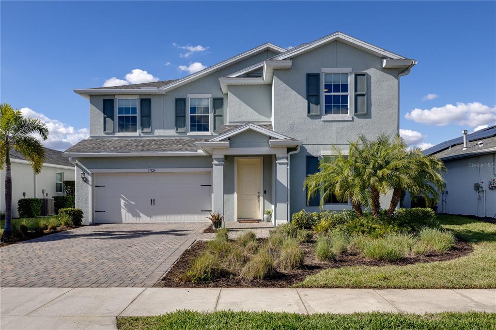 A two-story light blue house with a two-car garage and a paved driveway — 17424 SILVERSPUR DRIVE, PUNTA GORDA, FL