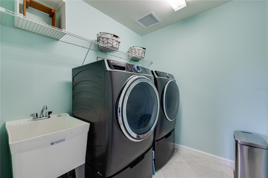 A laundry room features a utility sink, two dark appliances, and white wire shelving — 17424 SILVERSPUR DRIVE, PUNTA GORDA, FL