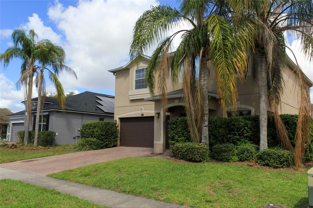 A two-story tan house with a brown garage door and palm trees in the front yard — 12927 BOGGY POINTE DRIVE, ORLANDO, FL