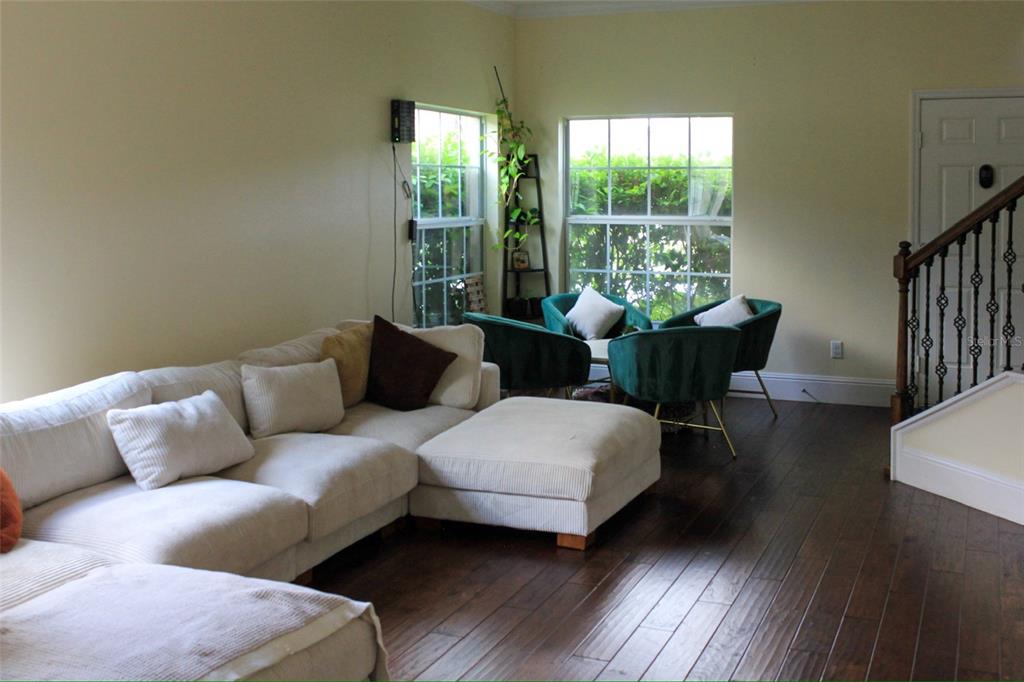 A living room features a large white sectional sofa, dark wood floors, and green chairs — 12927 BOGGY POINTE DRIVE, ORLANDO, FL