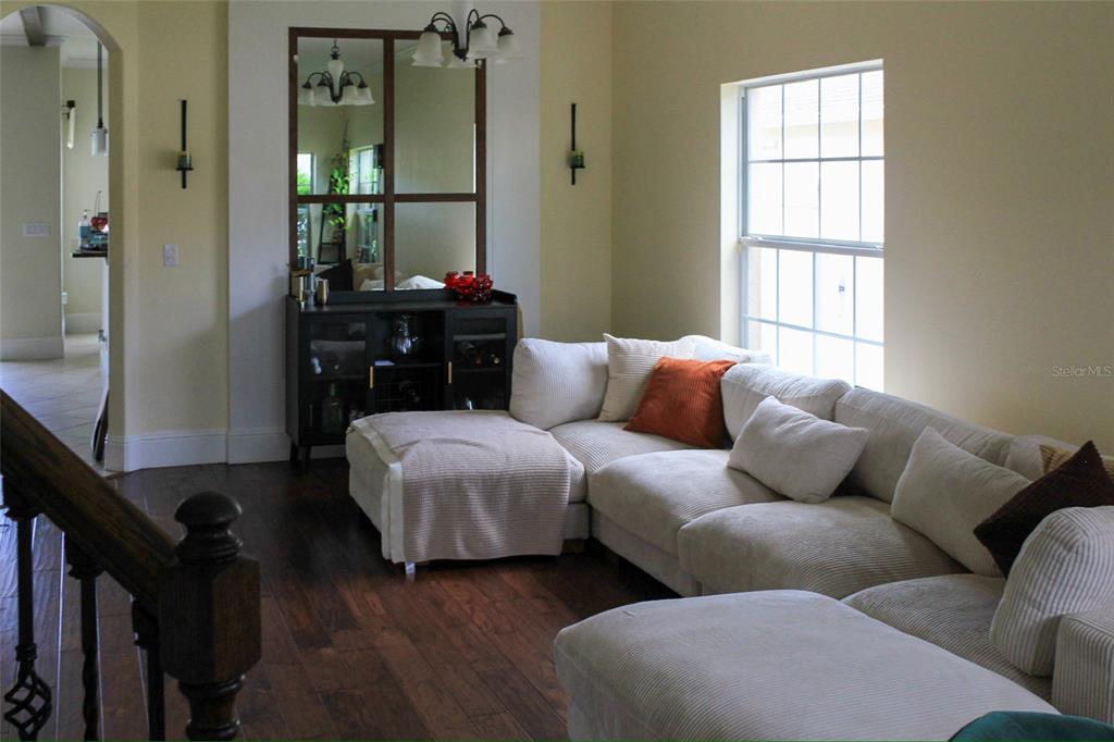 A living room features a white sectional sofa, a dark wood console, and a large mirror — 12927 BOGGY POINTE DRIVE, ORLANDO, FL