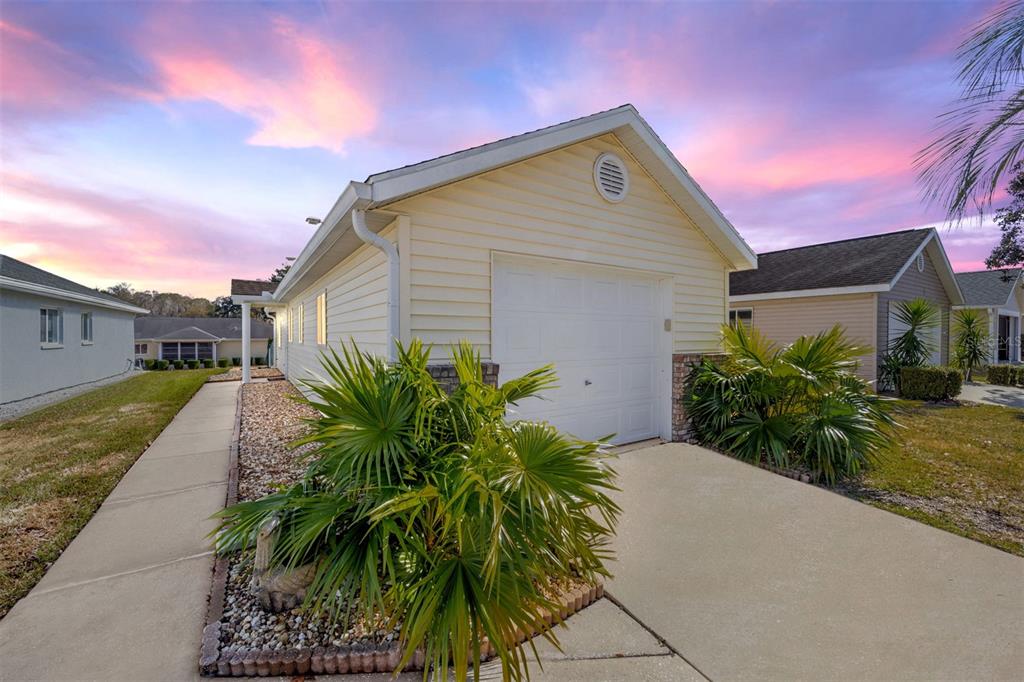 A light yellow house with a white garage door and a palm tree in front — 1921 NW 50TH CIRCLE, OCALA, FL