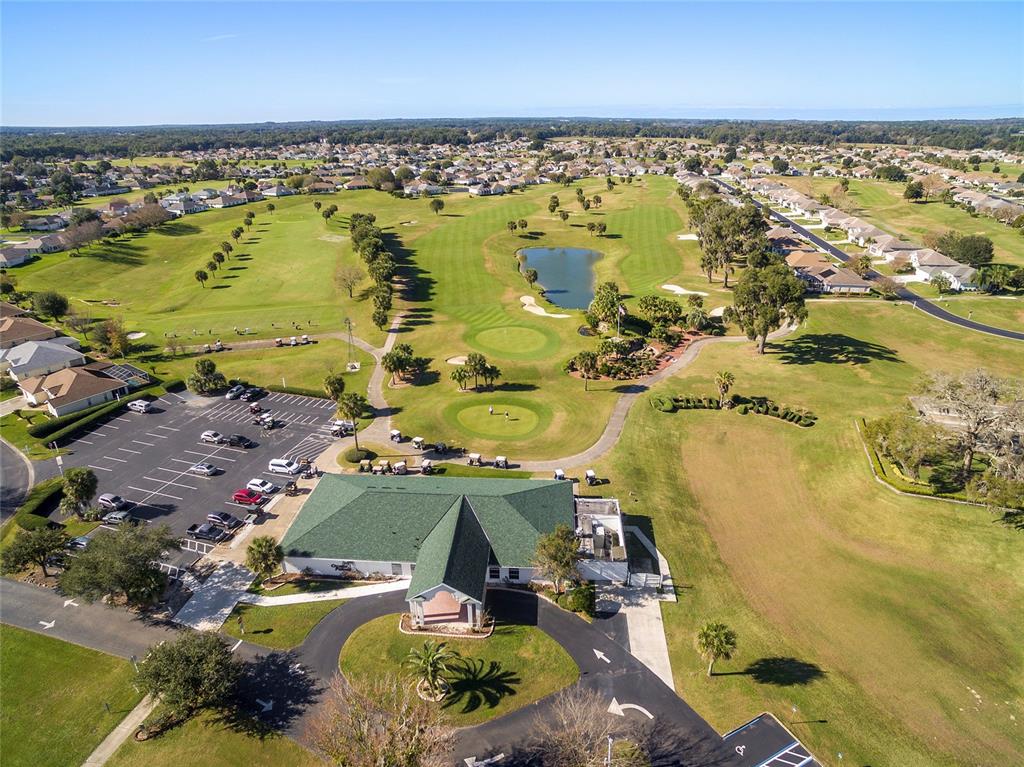 An aerial view shows a golf course clubhouse with a parking lot and surrounding greens — 1921 NW 50TH CIRCLE, OCALA, FL