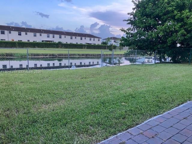 A grassy backyard features a chain-link fence overlooking a small canal and residential buildings — 10240 SW 227th Ln, Cutler Bay FL 33190, CUTLER BAY, FL